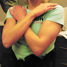 A woman touching her shoulders with crossed arms