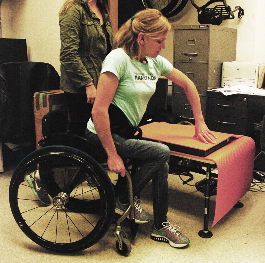 A woman moving over from a wheelchair to a table