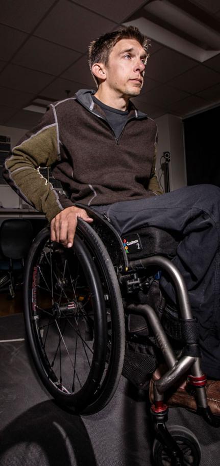 A man seated in a wheelchair preparing to use it